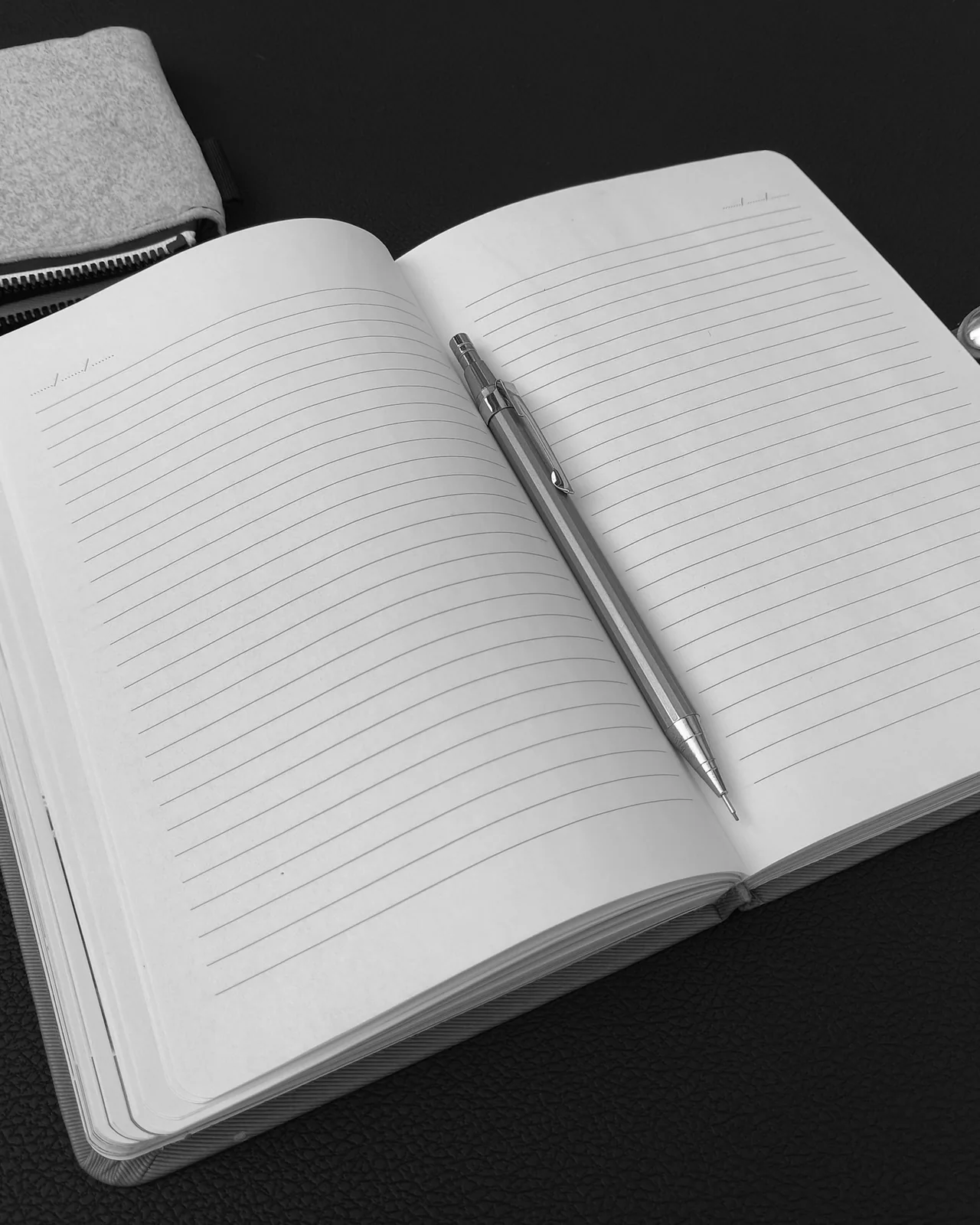Open notebook and pen on a desk, in black and white